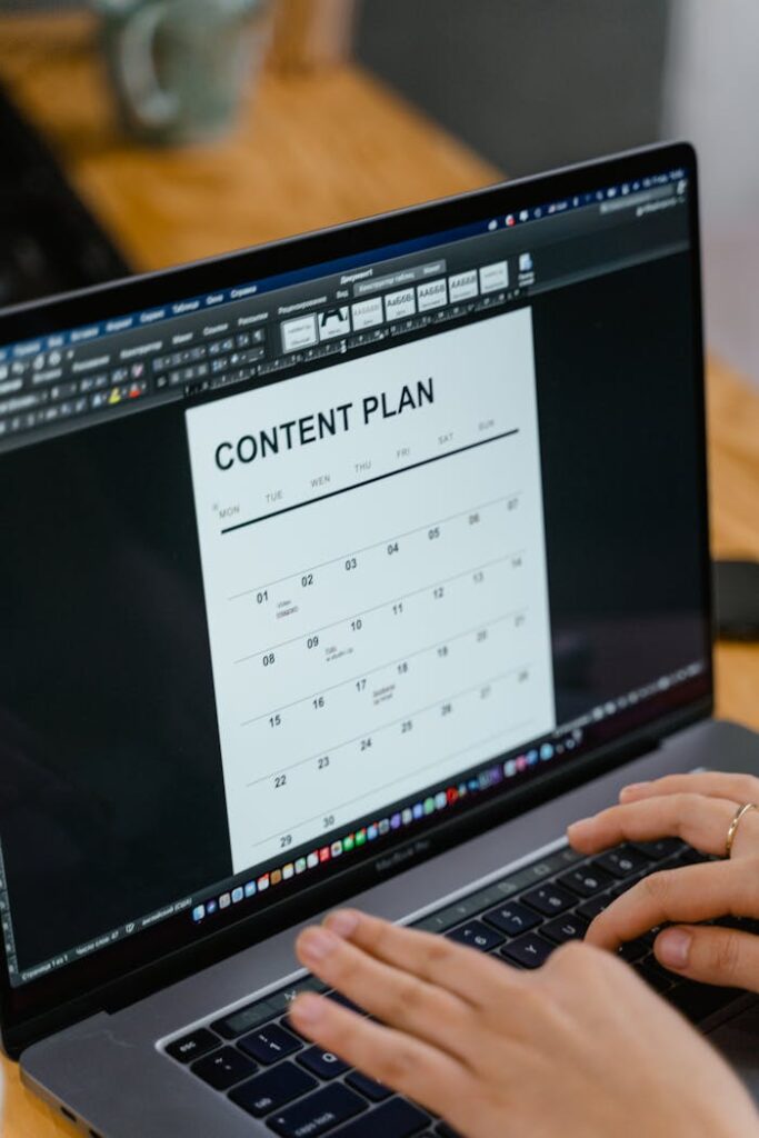 pexels photo 7679733 Close-up of hands typing on a laptop displaying a content plan document, ideal for business or marketing content.