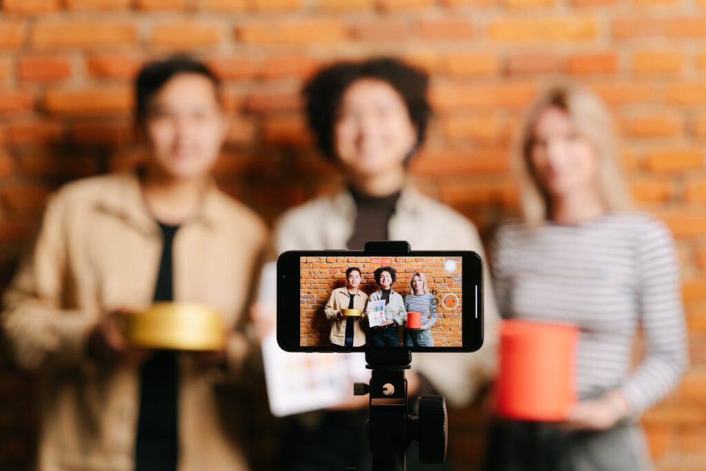 pexels photo 8117815 A diverse team of vloggers recording a video with a smartphone against a brick wall backdrop.